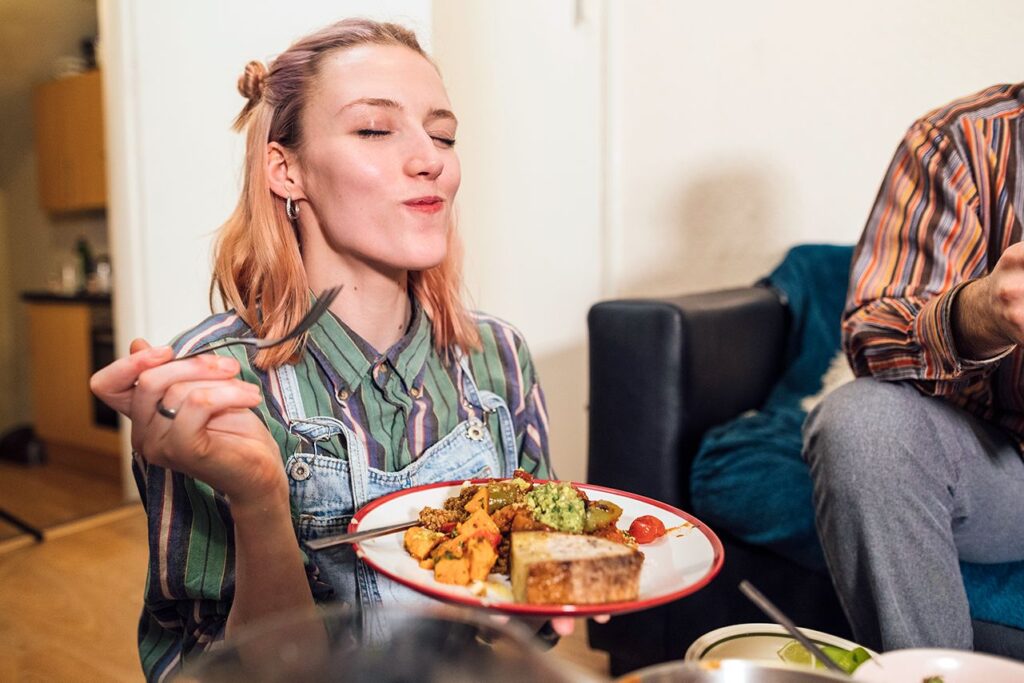 A woman smiles holding a plate of food