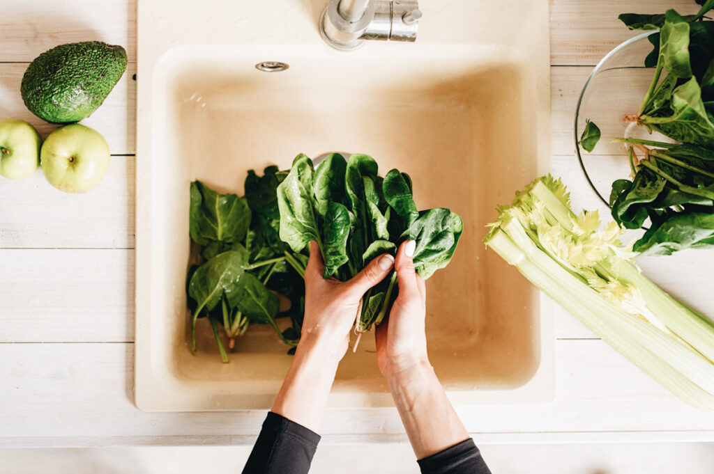 Photo shows someone holding dark leafy greens on a chopping board.