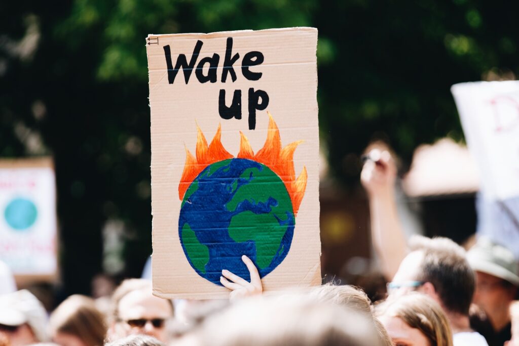 Photo shows a banner held aloft by a protester that shows the earth on fire with "wake up" written above.