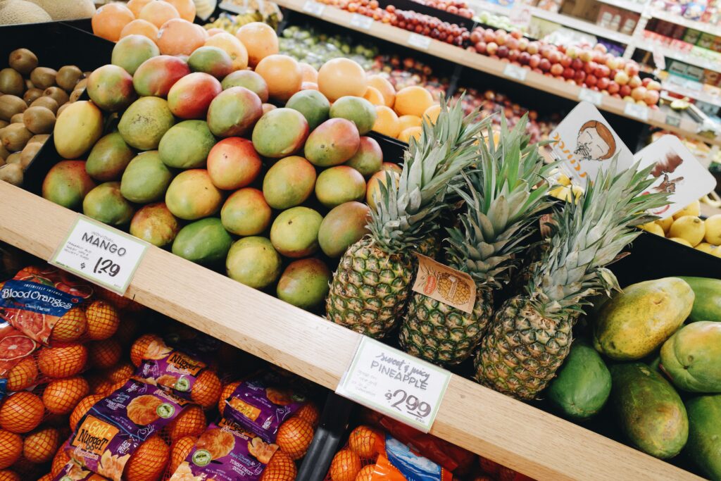 A produce aisle with mangoes and pineapples.