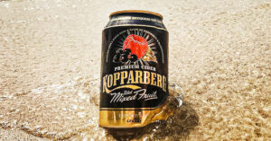 Photo of Kopparberg Mixed Fruits cider (which is now vegan) in the water at the beach.