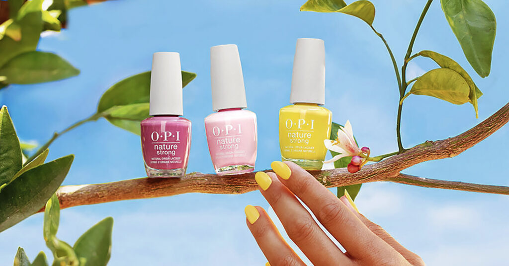 Photo shows a hand with painted nails reaching for the OPI vegan nail polish collection as it sits on a branch.