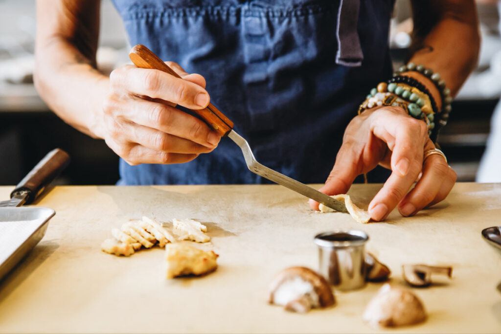 Photo shows Dominique Crenn preparing Upside Foods' cultured meat to serve in her restaurant, Atelier Crenn.