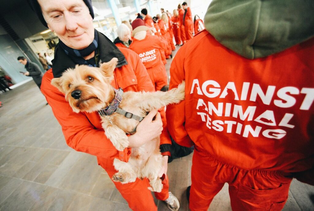 A man holding a dog at a cosmetic animal testing protest