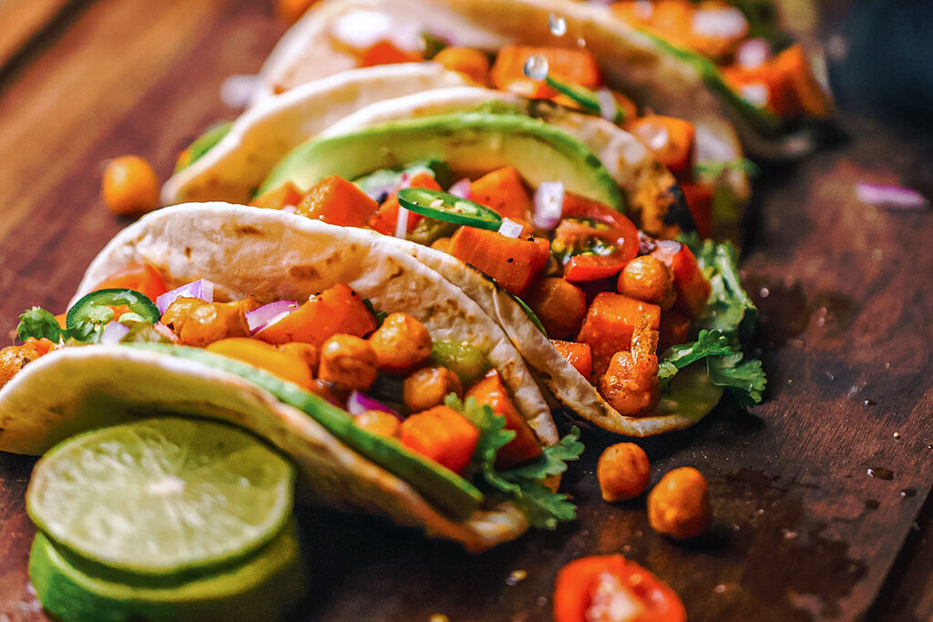 Photo of vegetable-filled tacos with lime, coriander, and avocado.