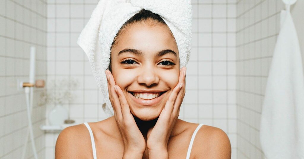 A woman smiles with a bath towel around her hair