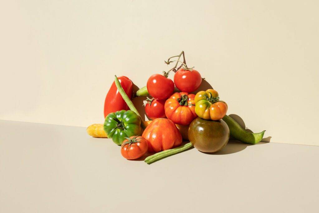 Photo shows a pile of fresh produce, including green beans and vibrant, varied tomatoes. Here are some of the science-backed benefits of a plant-based diet.