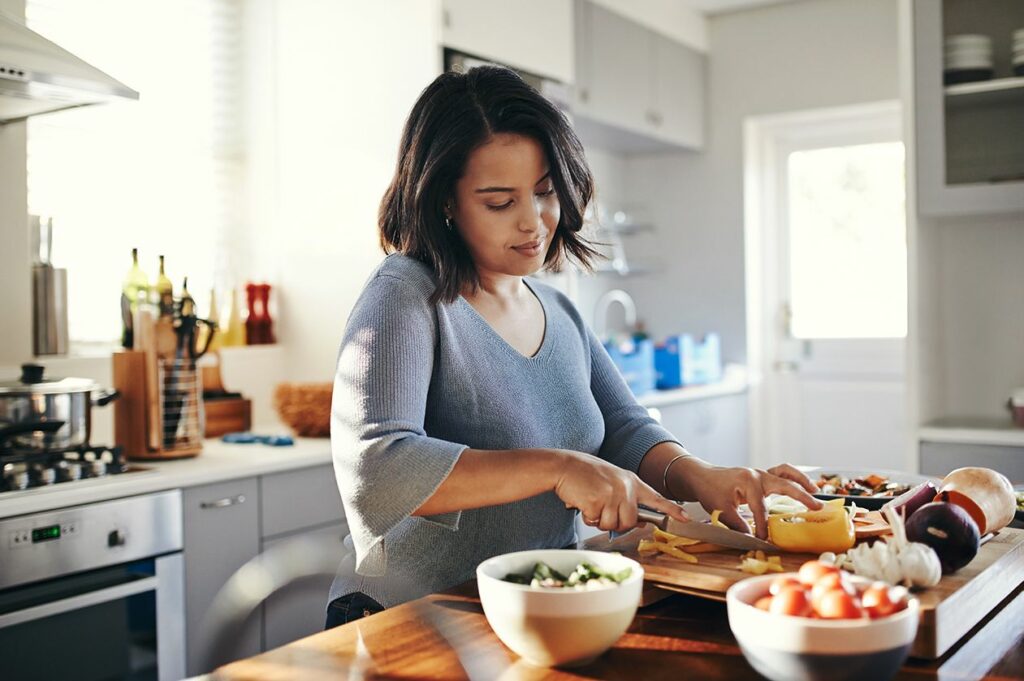 How the Rising Price of Meat Hurts Everyone. a woman chopping vegetables