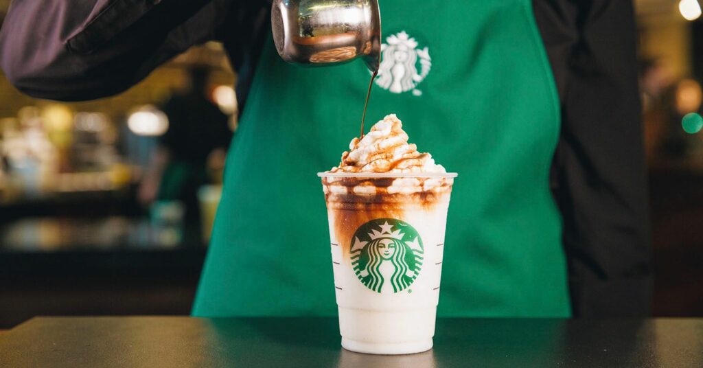 A Starbucks barista makes a cafe drink with whipped cream