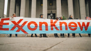 Photo shows protestors standing outside of New York Supreme Court in 2019. They hold a huge banner that reads "Exxon knew." The trial accused the Big Oil company of misleading its investors over climate-related financial risks.