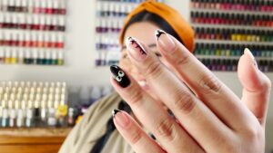 A woman holds up Halloween-inspired nails in front of her face