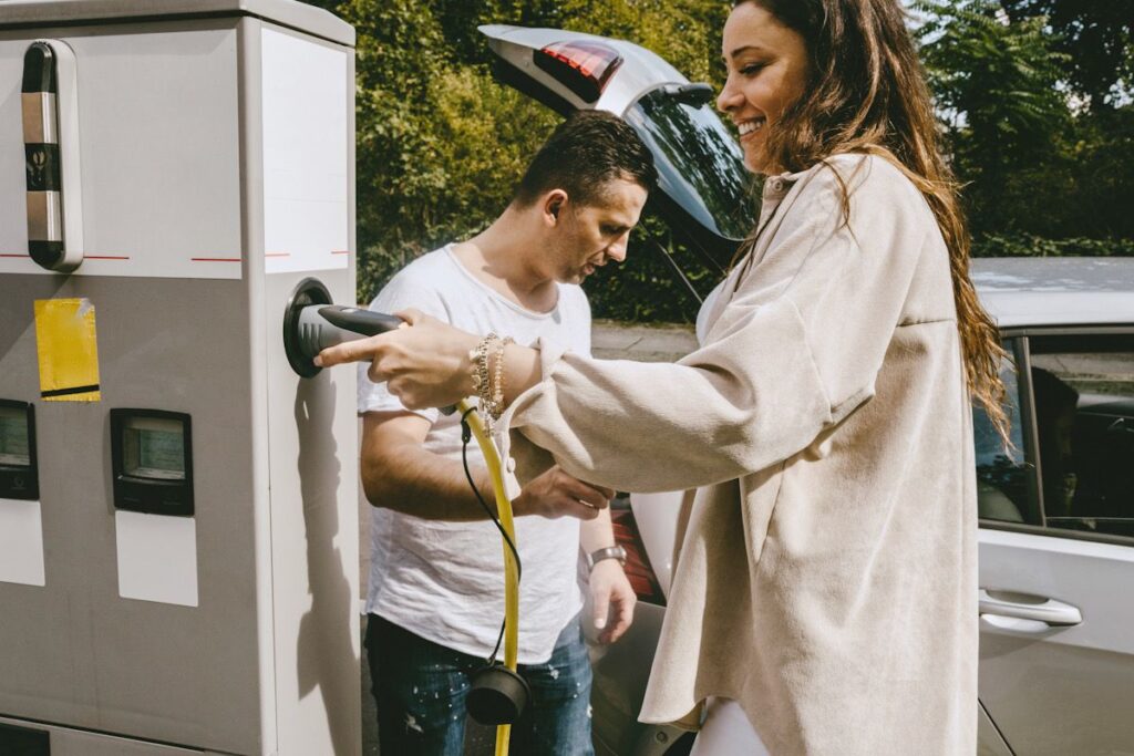 A woman and a man stand next to an electric charging point