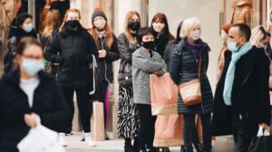shoppers wearing masks queue, some with Primark bags