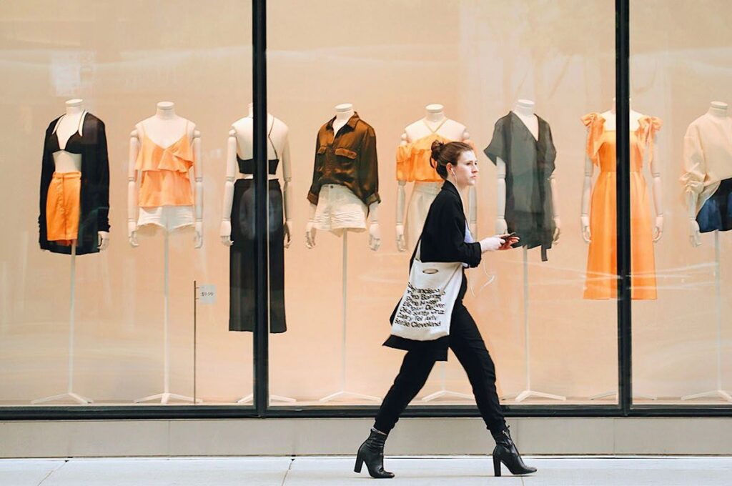 A woman walks past a clothing store window