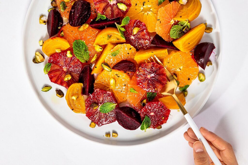 Photo shows a salad of roasted beets and various slices citrus fruits topped with pistachios and mint