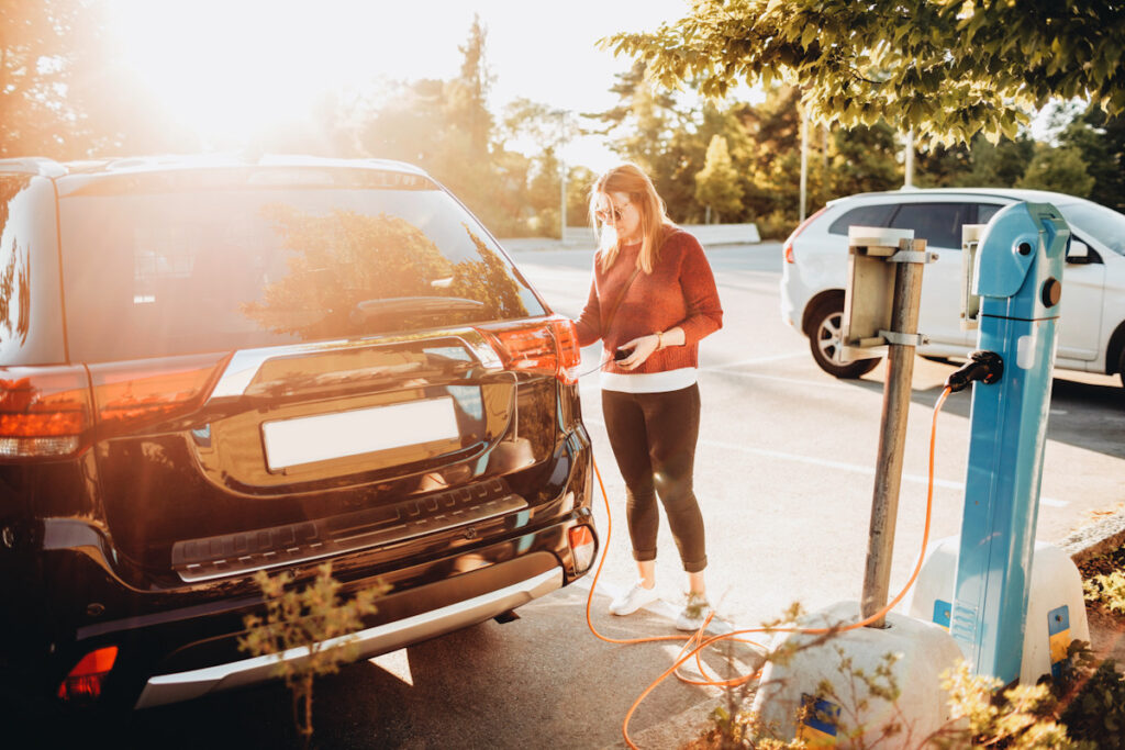 Photo shows a woman plugging in a large electric car to charge. 2021 saw several new environmental laws introduced to support electrification, and 2022 is sure to follow suit.