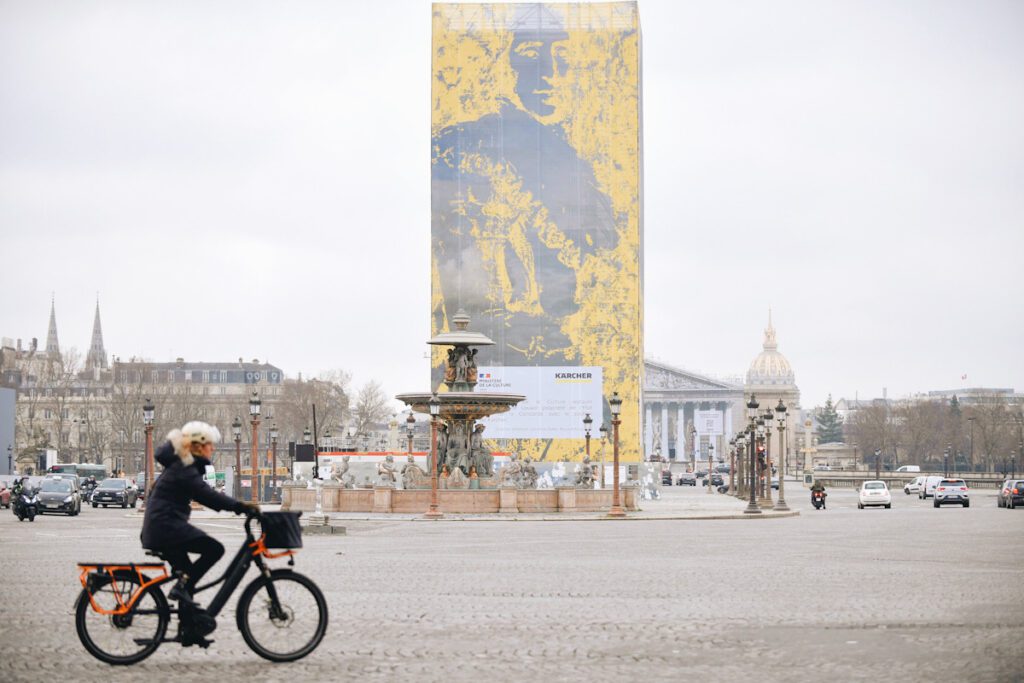 Photo shows a cyclist riding next to the Obelisk of Luxor on the Place de la Concorde in Paris, France.