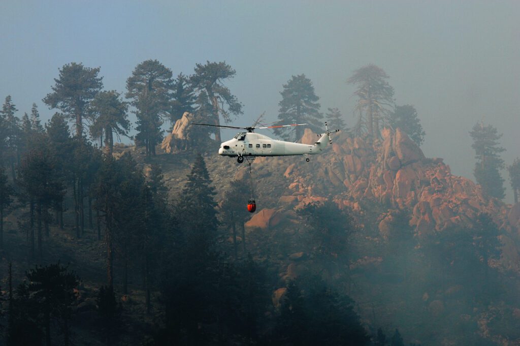 Photo shows a firefighting helicopter, flown by Carson Helicopter Services near Fawnskin, California. The state has seen several winter wildfires over the last few months.