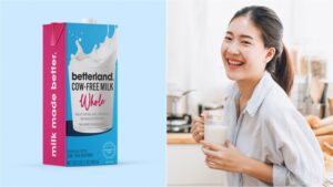 Photo shows a carton of Betterland Foods milk split with a woman holding a glass of milk and smiling