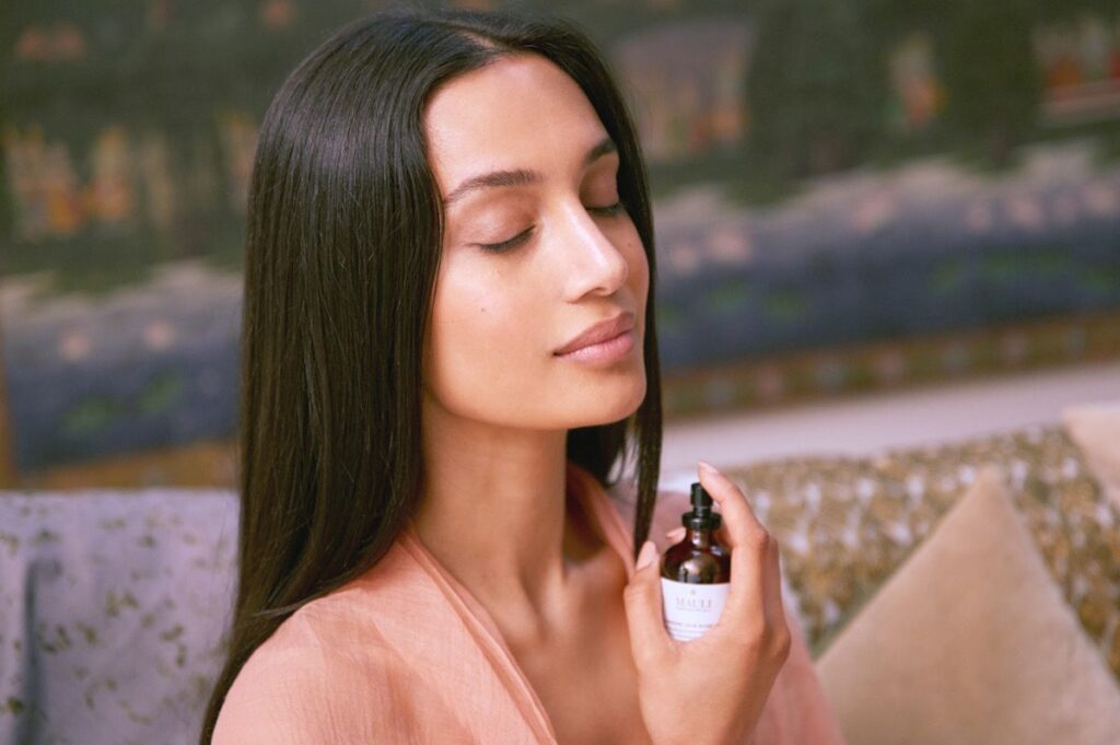 a woman holds a mist up to her face