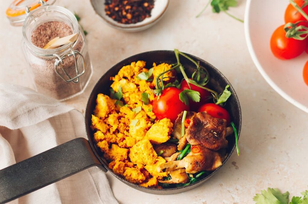 A frying pan with tofu scramble and tomatoes