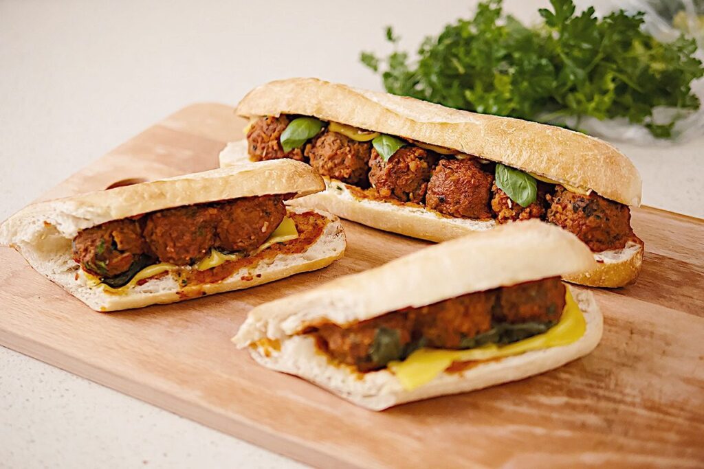 Photo shows three plant-based meatball subs on Italian bread