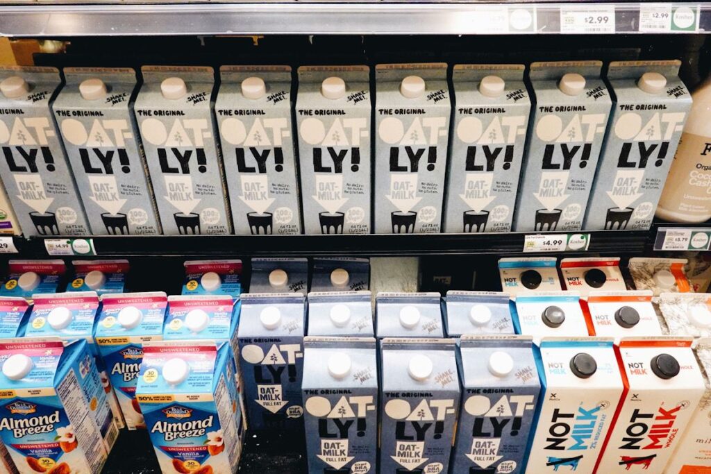 Photo shows a variety of plant-based milks--oat, AI-generated, almond--in the milk aisle.