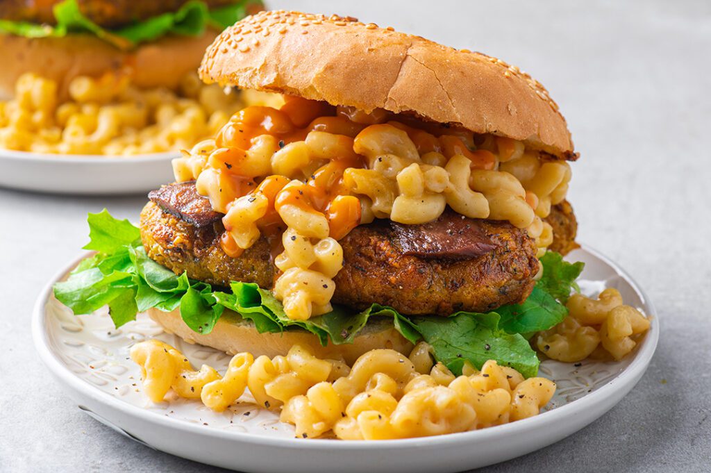 Photo shows a large mac-n-cheese burger with green salad.