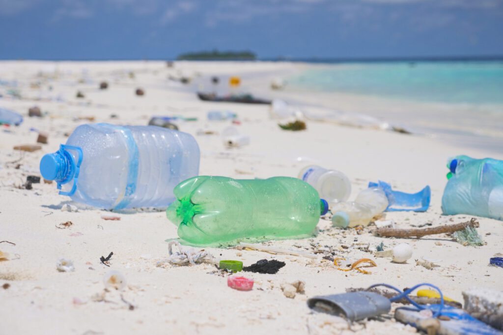 Photo shows plastic bottles and other trash littered on a white sand beach. The UN plastic treaty, which is still being negotiated, could help to halt such extreme plastic pollution.