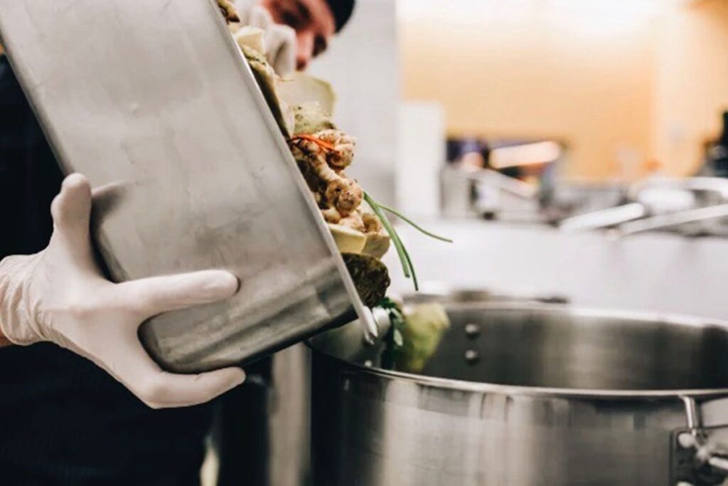 Photo shows a Google employee dumping food scraps into a pot
