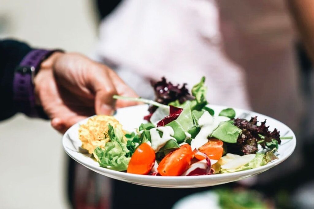 Photo shows a Google employee's hand holding a plate of salad