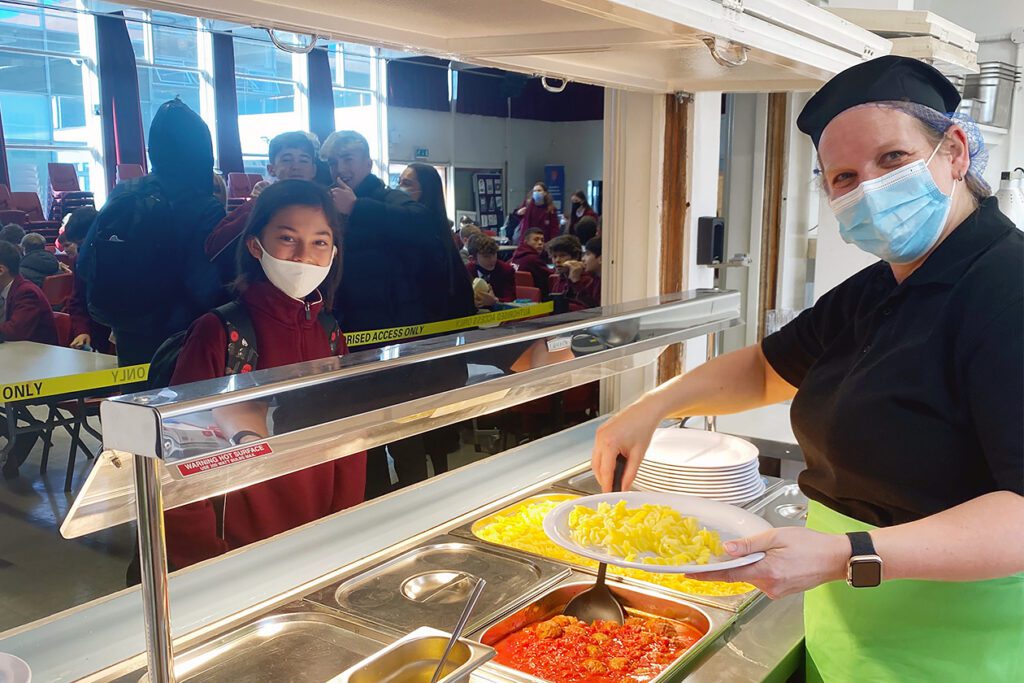 Photo shows one of the cooks at the UK's Our Lady of Sion school dishing up vegan lunches to hungry pupils.
