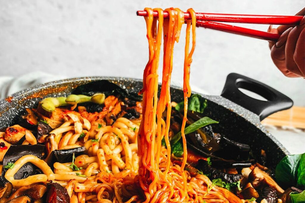 Photo shows a vegan hot pot made with lots of noodles and mushrooms