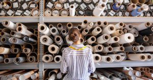 Photo shows a woman from behind as she peruses shelves of fabric. So what exactly is deadstock?